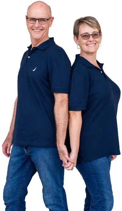 Smiling couple standing back-to-back, holding hands, representing local real estate professionals who buy houses in Monroe County, Indiana